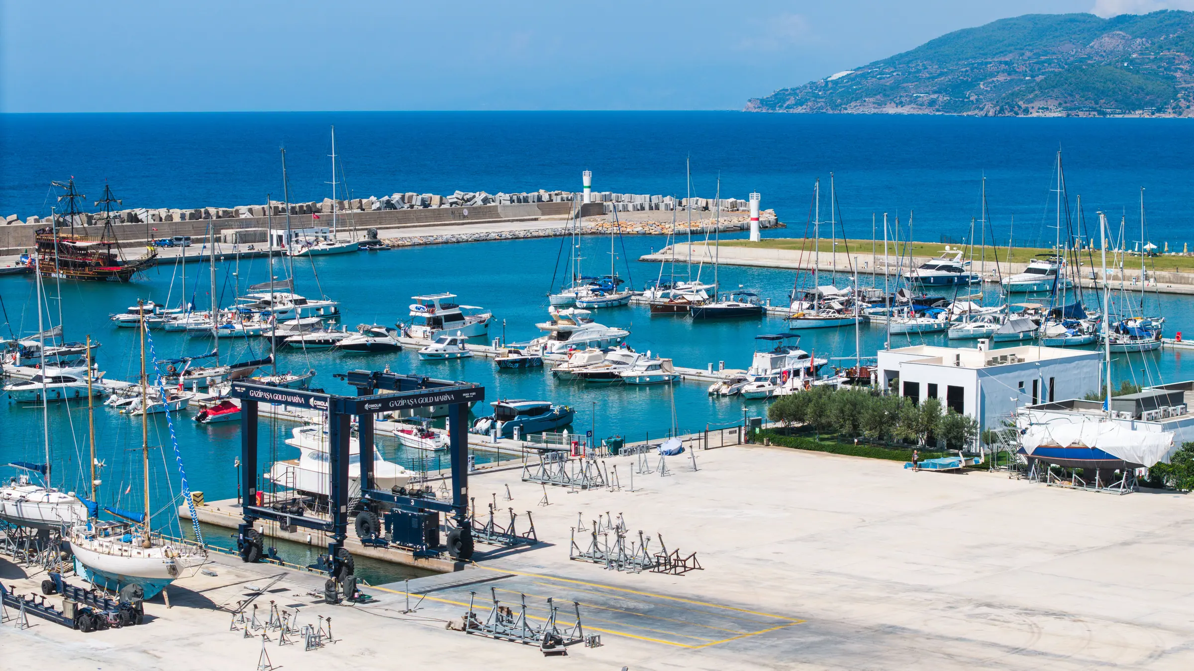 Travel lift, çekek sahası ve arkasında yatlarla dolu bağlama havuzu